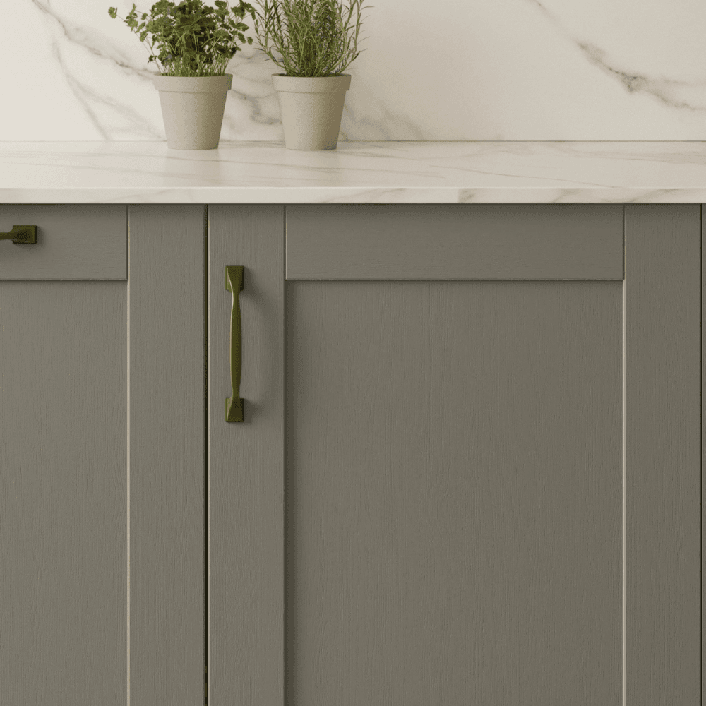 Close up of green shaker door with brass handles and white worktop