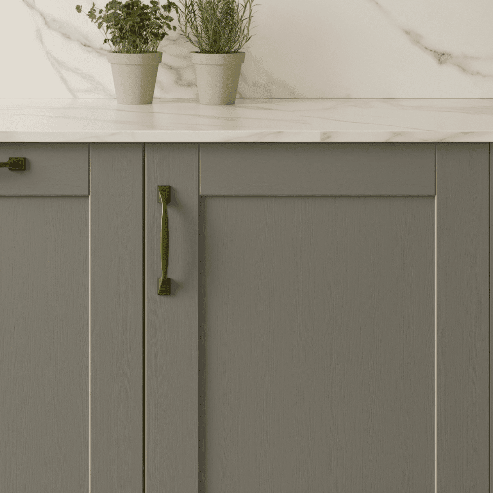 Close up of green shaker door with brass handles and white worktop