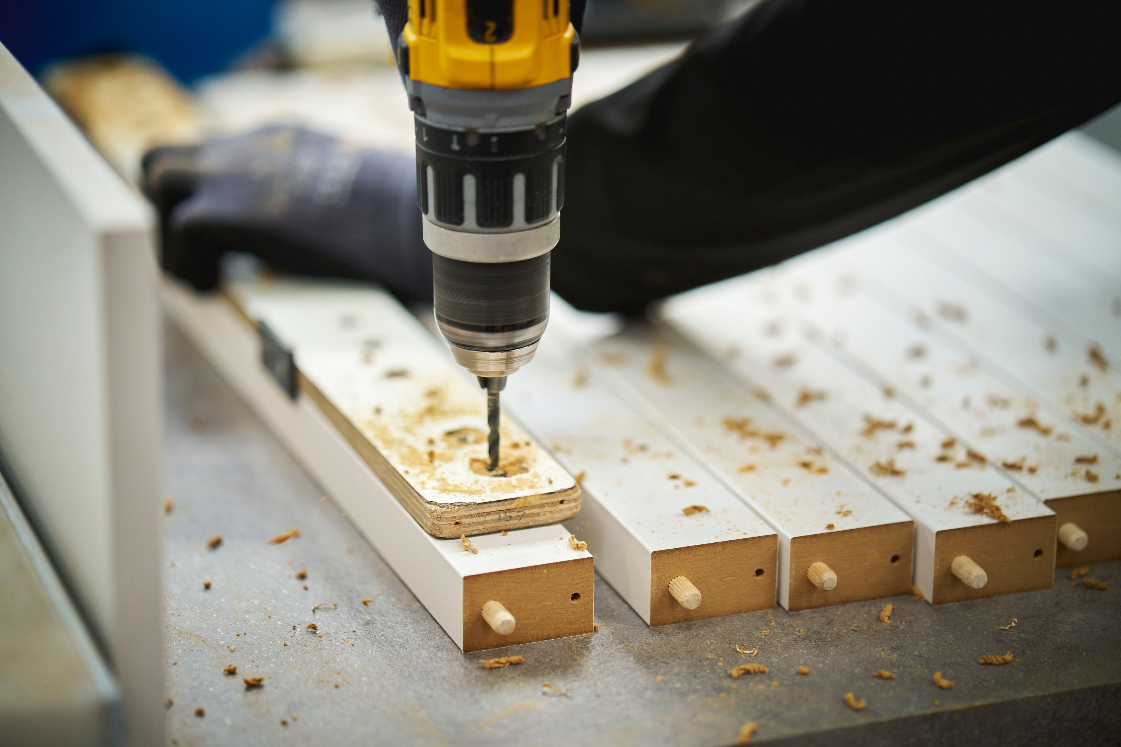 Person using a drill to build a cabinet in a factory